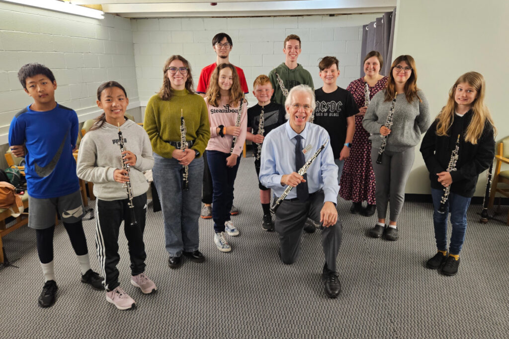 A group of kids posing with a professor. Some are holding obos.